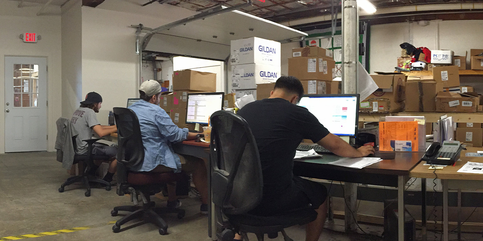 Photograph of men sitting at desks working on computers